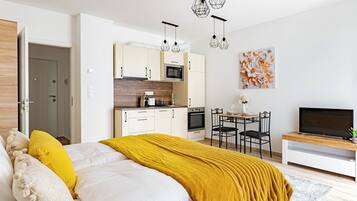 A modern bedroom with a bed, a dining area, and a kitchen.