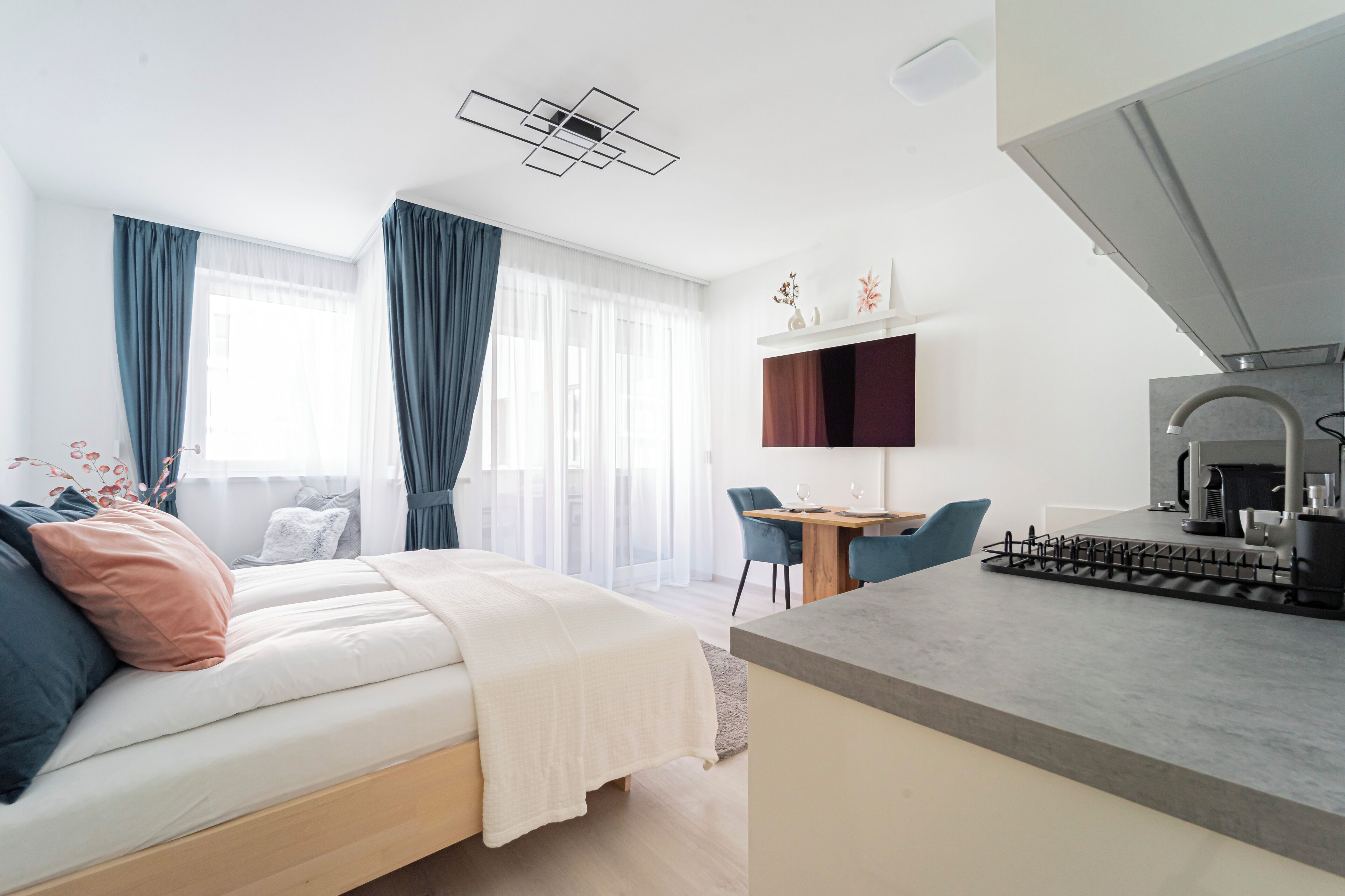 Un dormitorio moderno con cama, escritorio y kitchenette.