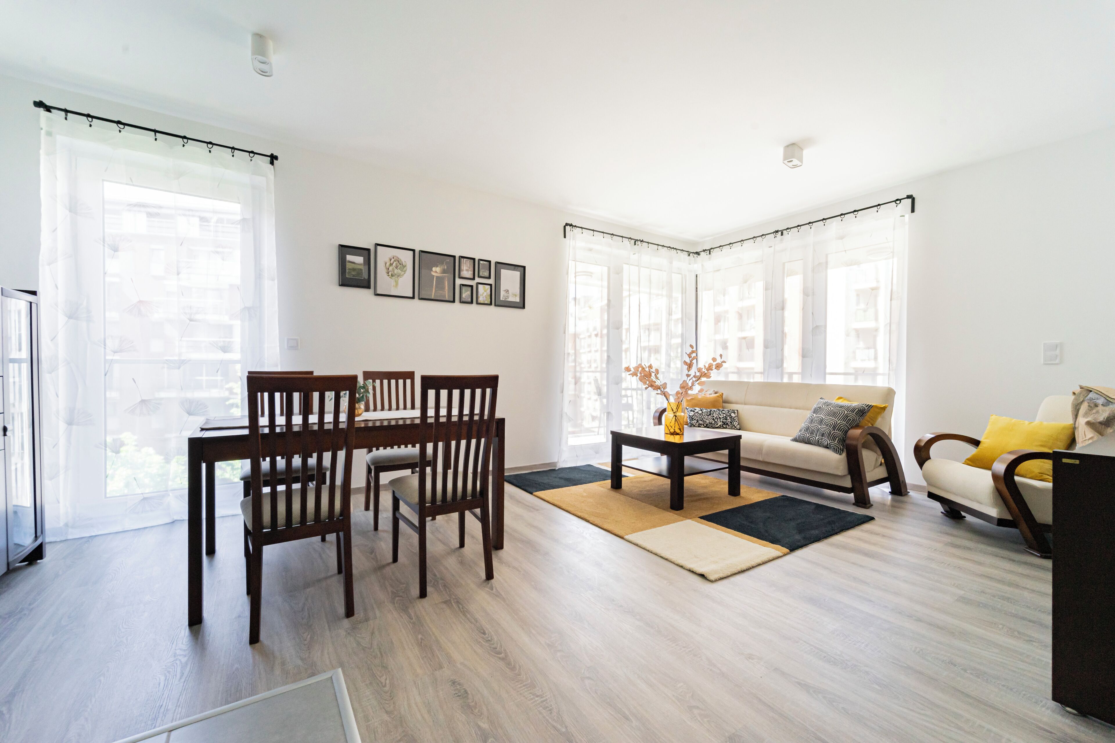 A modern living room with a dining area, featuring a sofa, chairs, a coffee table, and a TV.