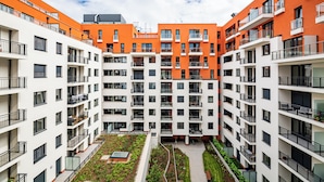 Un edificio residencial de varios pisos con balcones, un patio central con vegetación y un cielo despejado.
