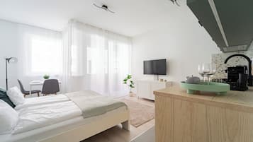 Une chambre d’hôtel moderne équipée d’un lit, d’un bureau, d’une télévision et d’une kitchenette.