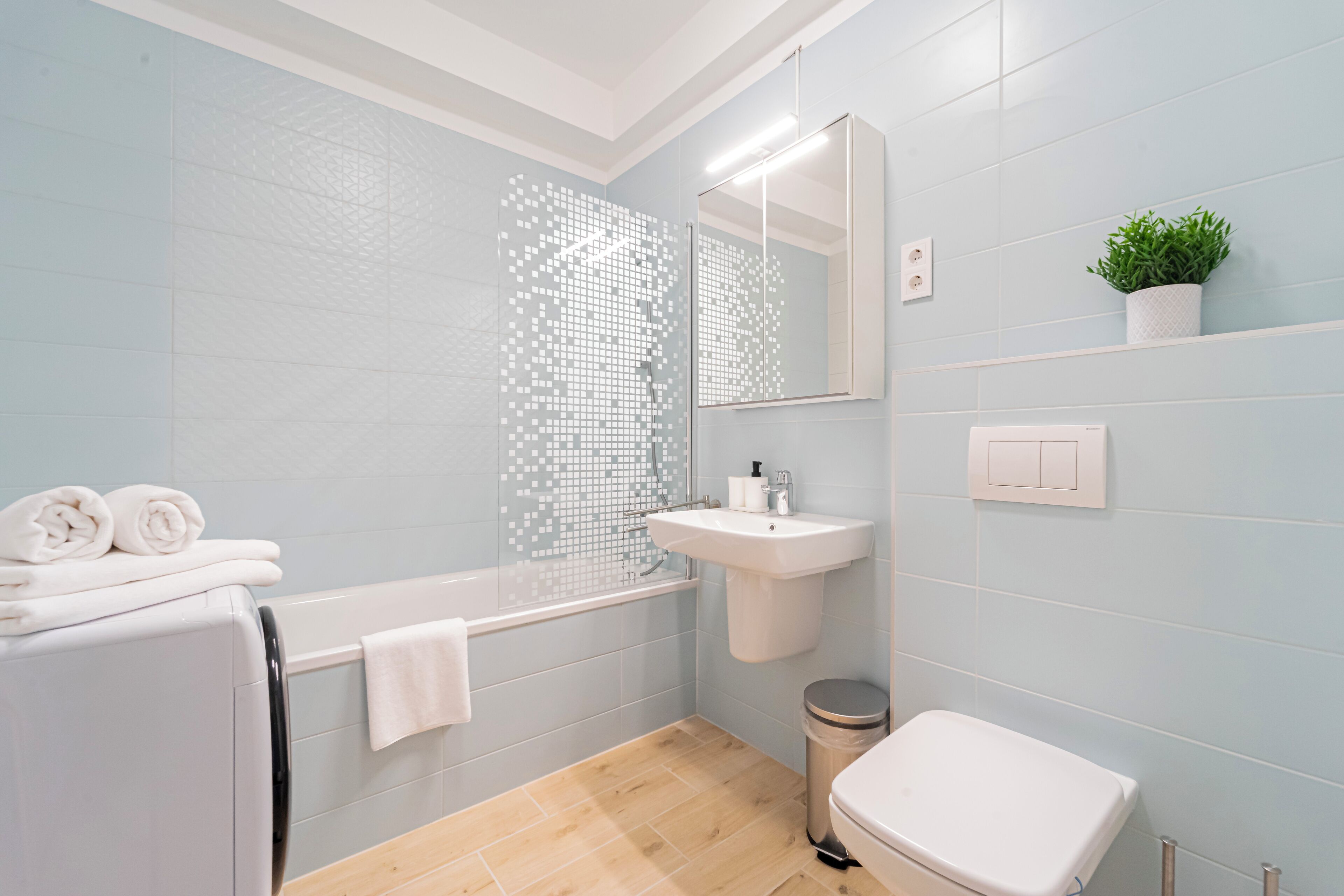 A modern bathroom with a bathtub, sink, toilet, and a mirror.