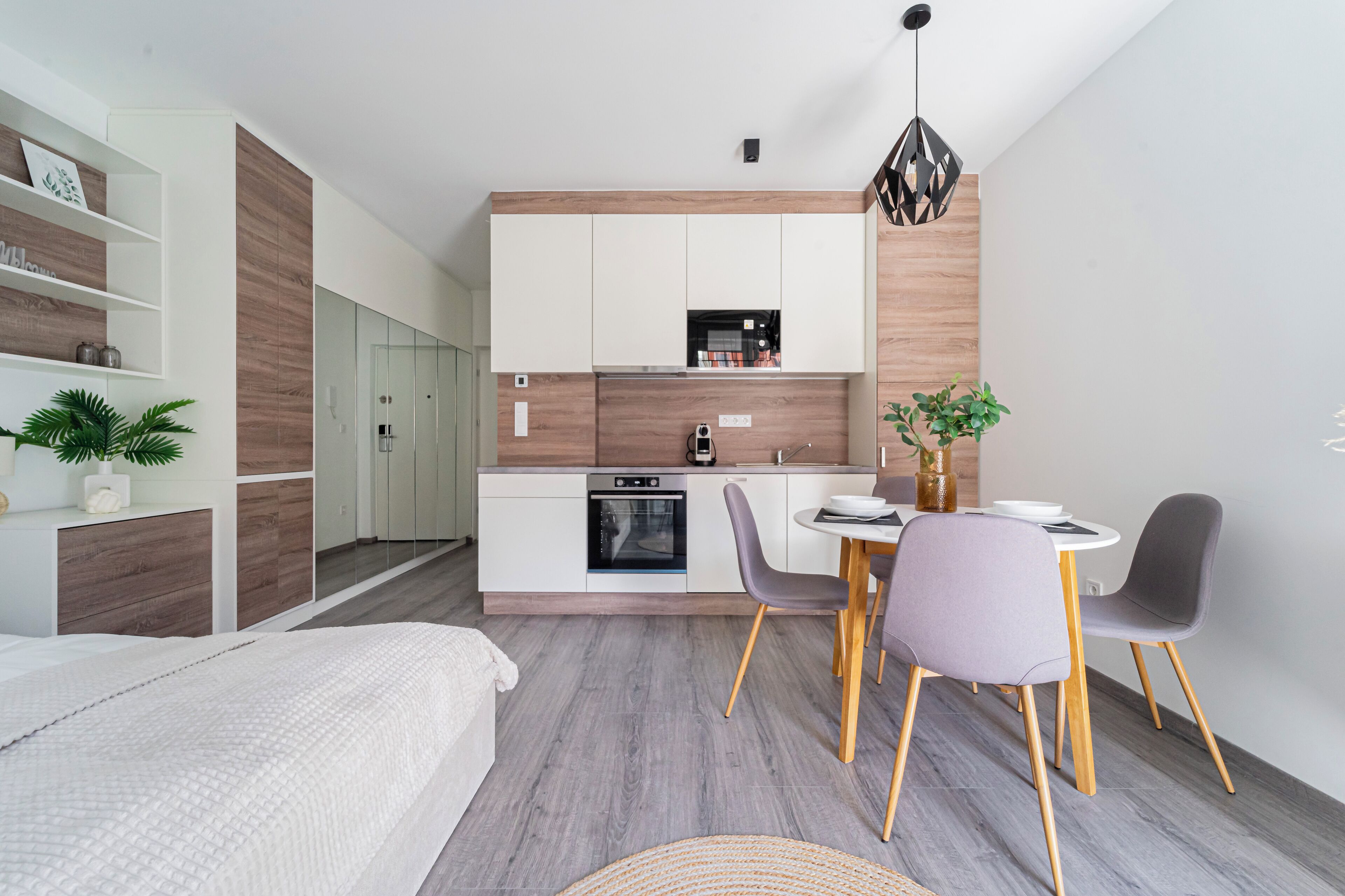 A modern, compact living space with a kitchenette, dining area, and a bed.