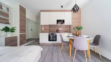 A modern, compact living space with a kitchenette, dining area, and a bed.