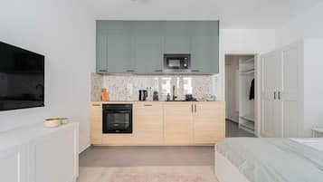 A compact bedroom with a bed, a small kitchenette with a microwave, and a built-in oven.