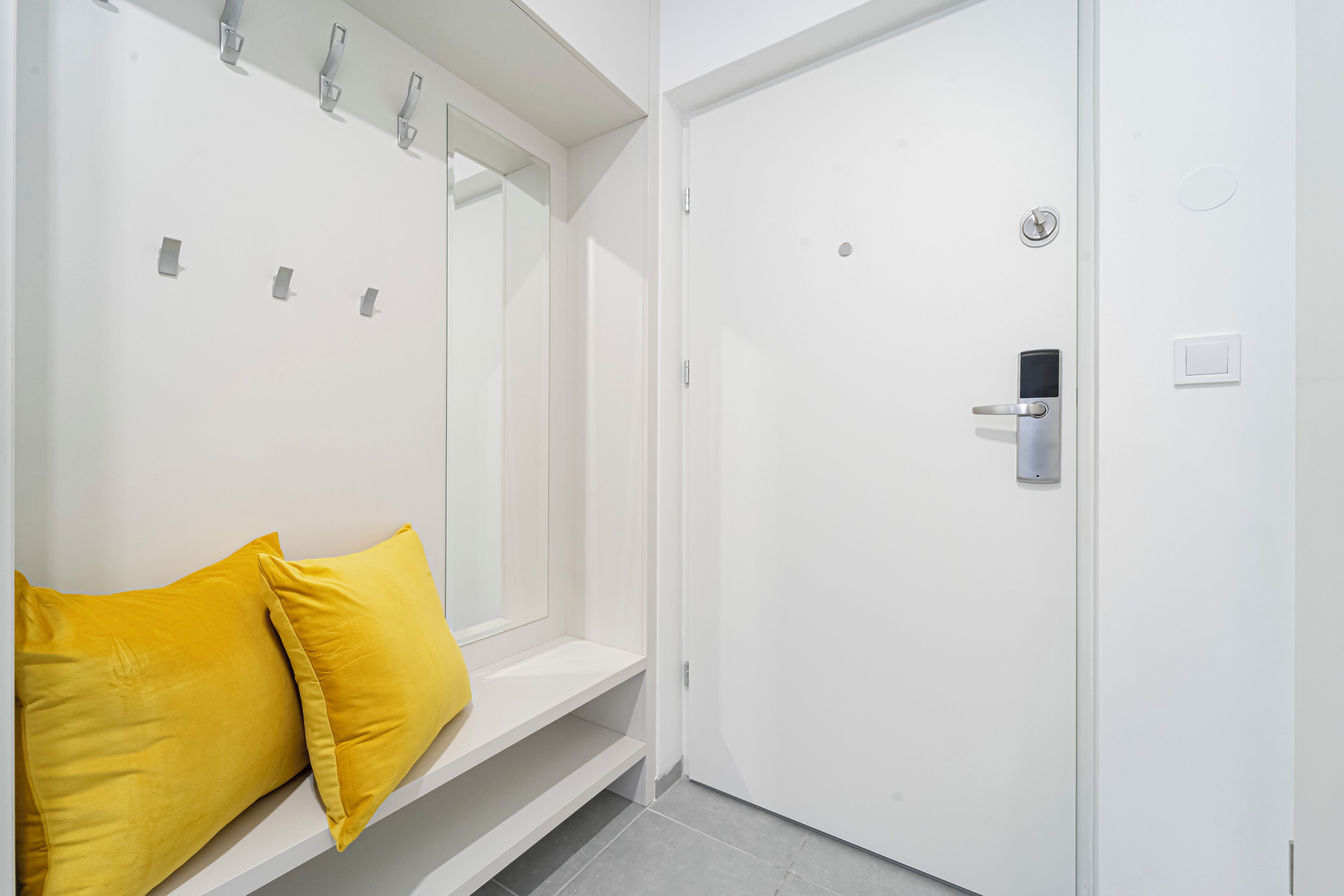 A white door with a digital lock, a small shelf, and two yellow pillows.
