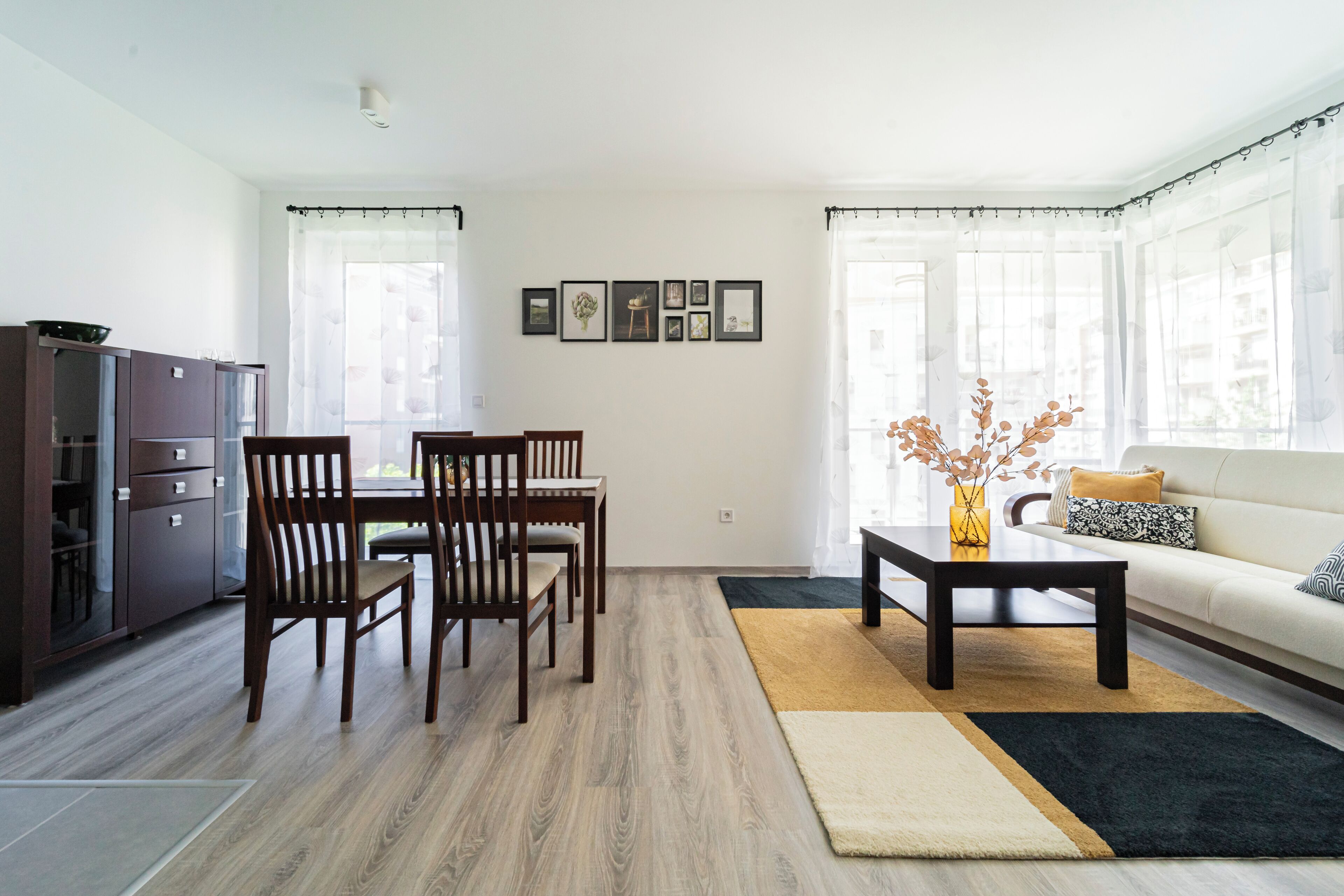 A modern living room with a dining area, featuring a sofa, coffee table, and dining table with chairs.