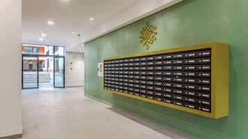 A hallway with a green wall, a yellow display case with nameplates, and a glass door leading outside.