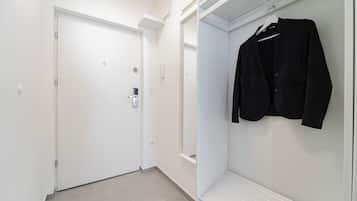 Een gang met een witte deur en een kast met een kapstok.