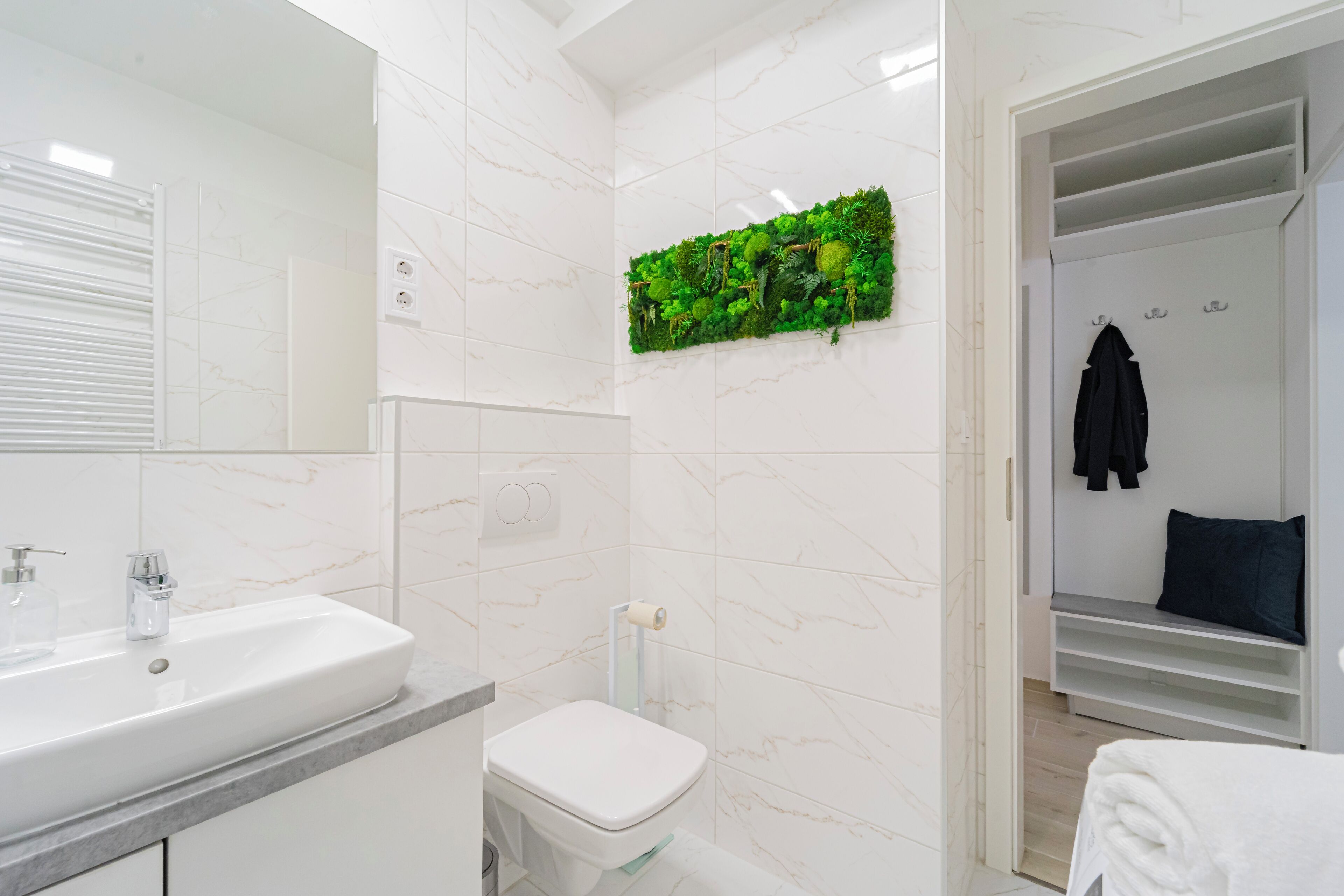 Un baño moderno con lavamanos, inodoro y un adorno de pared verde.