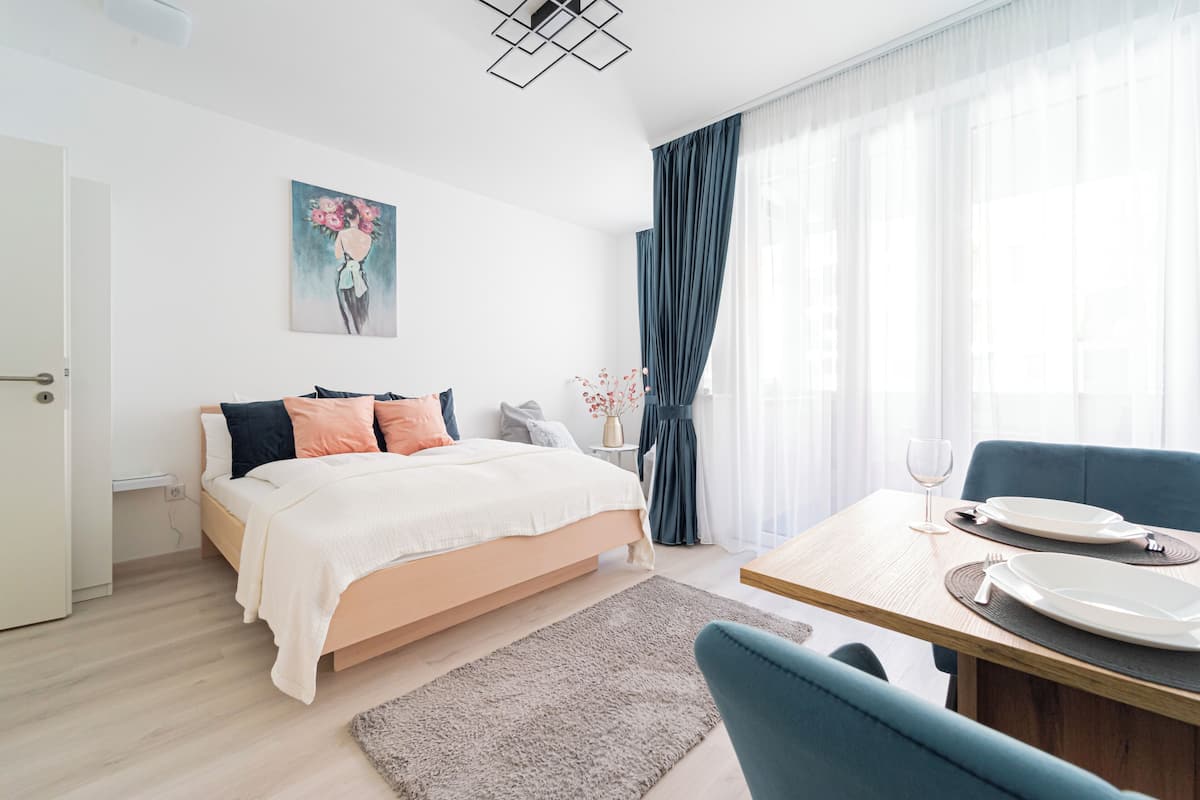 Ein modernes Schlafzimmer mit Bett, Nachttisch und einer Essecke mit Tisch und Stühlen.