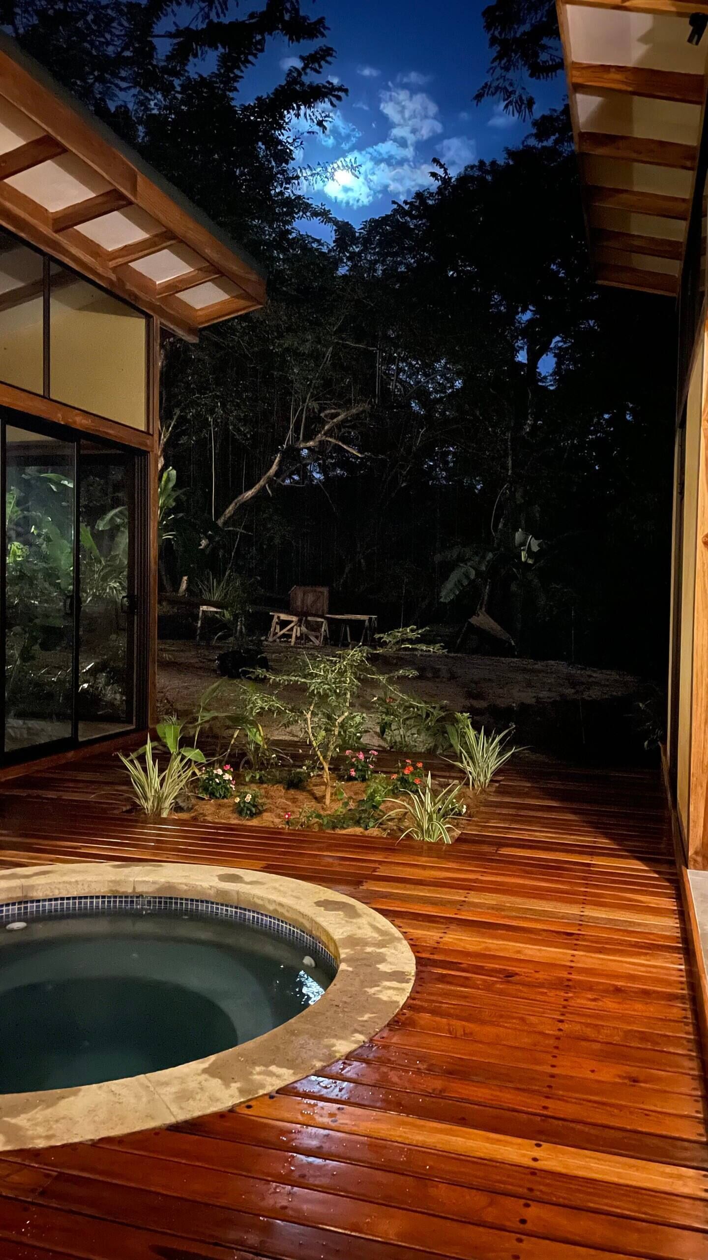A wooden deck with a pool, surrounded by a garden with various plants and flowers.
