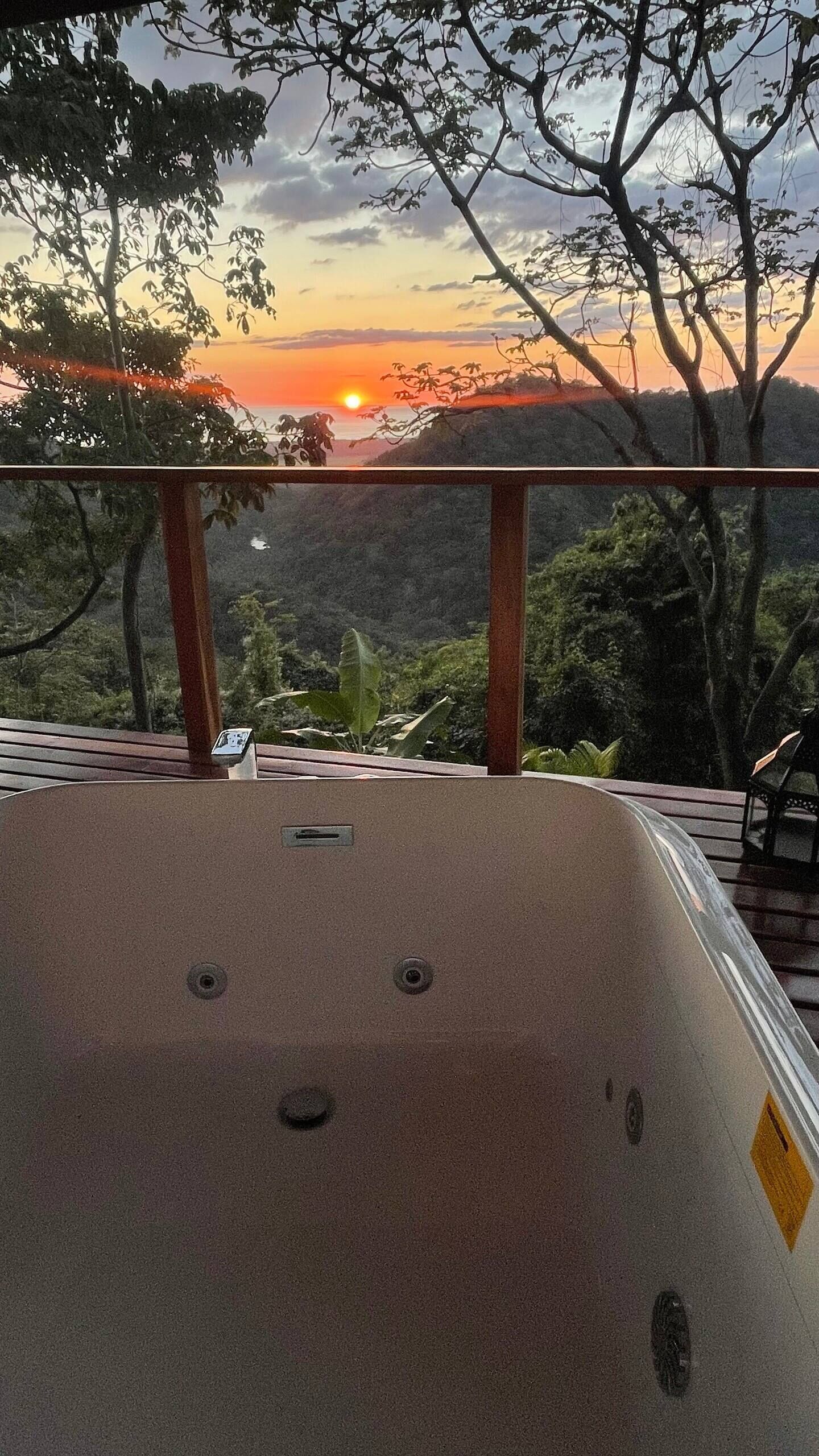 Ein Whirlpool mit Blick auf einen Sonnenuntergang über einer Berglandschaft.