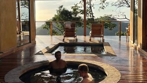 Une terrasse en bois avec un jacuzzi et des chaises longues, offrant une vue imprenable sur un paysage magnifique.