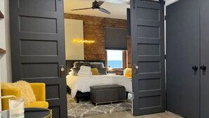 A modern bedroom with a bed, a yellow armchair, and a large wardrobe. - Timeless Loft -OTR -TQL w/ FREE Parking (Cincinnati)