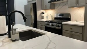 A modern kitchen with a black faucet, a stainless steel stove, and light grey cabinets. - Timeless Loft -OTR -TQL w/ FREE Parking (Cincinnati)