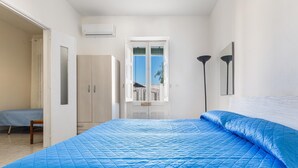 Une chambre à coucher avec un grand lit, une armoire, une fenêtre et une porte donnant sur une autre pièce.