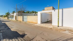 Une rue bordée d’un immeuble blanc, d’un mur de briques et d’un ciel d’un bleu limpide.