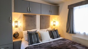 A bedroom with a large bed, grey cabinets, and two wall-mounted lamps.