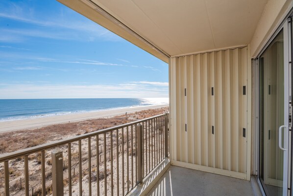 A balcony with a view of the beach and ocean.