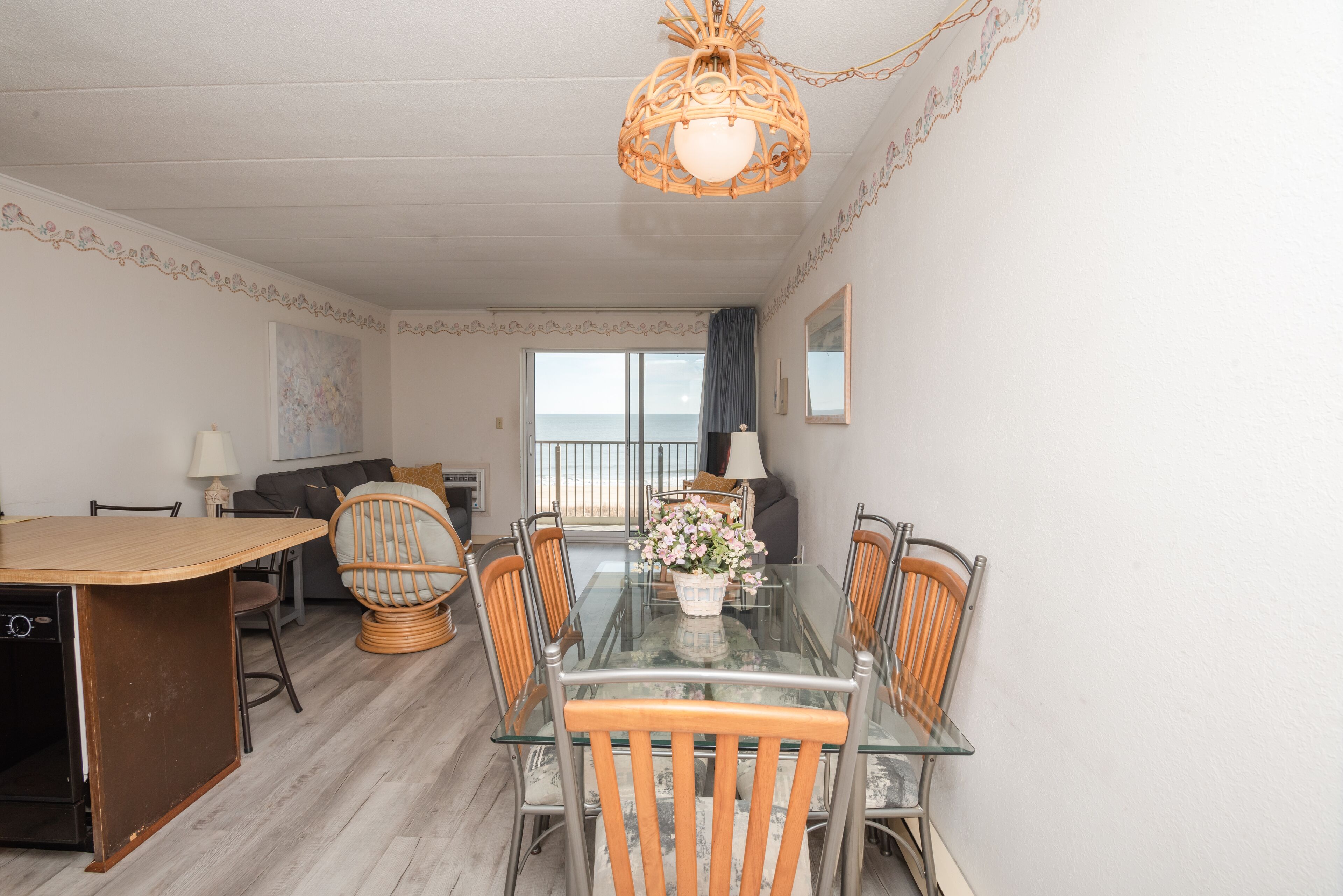 A dining area with a glass table, wicker chairs, and a decorative centerpiece.