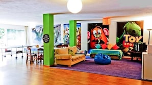 A room with a green accent wall, a sofa, a blue bean bag, and a large Toy Story 3 poster.