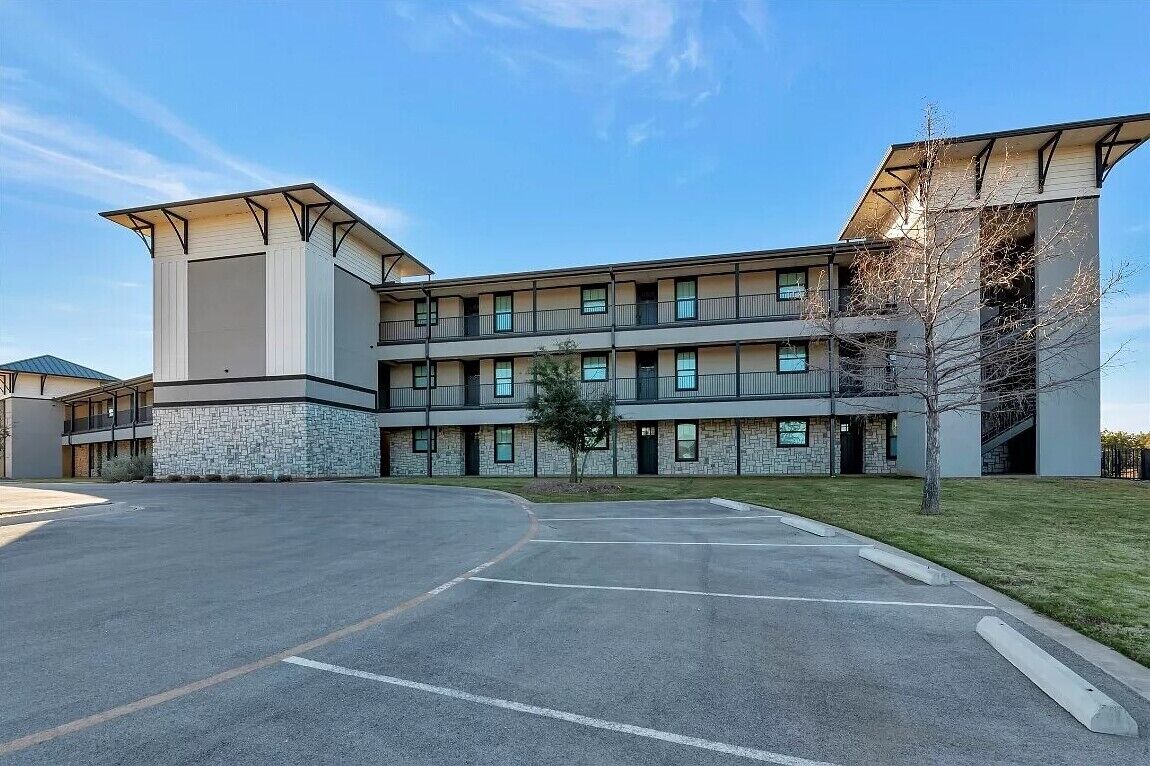 A multi-story hotel with a central courtyard, balconies, and a stone facade.
