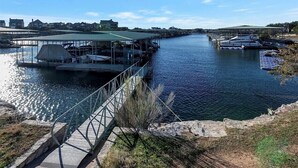 Un embarcadero a orillas del río con zonas de estar cubiertas y un puente peatonal.