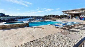 Zona de piscina con varias piscinas, sillas de descanso y una estructura cubierta.