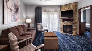A modern hotel room with a stone fireplace, a sofa, a wooden coffee table, and a television mounted on the wall. - 2Bed/2Bath Deluxe Suite at our Dells Resort w/Access to Wilderness Territory! (Baraboo)