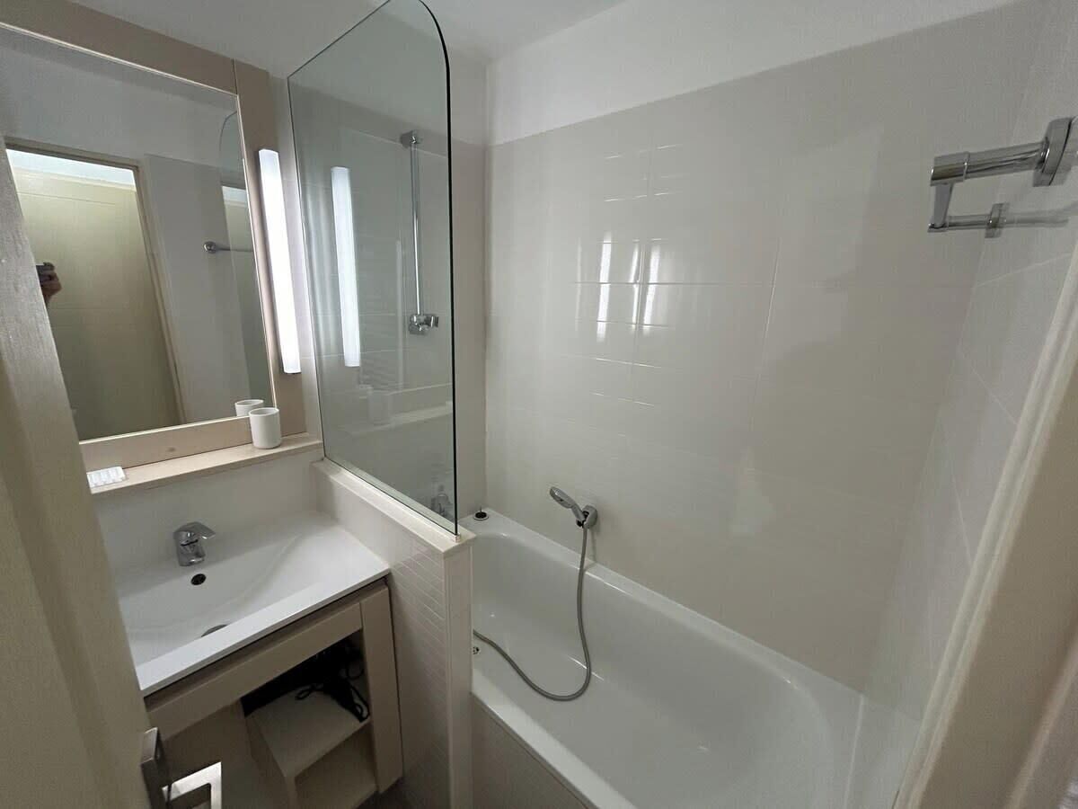 A bathroom with a sink, mirror, and a walk-in shower.