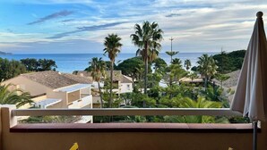 A balcony with a view of the sea, palm trees, and buildings. - L'Anse de Pramousquier, T2 Vue Mer ! Bord de plage (Le Lavandou)