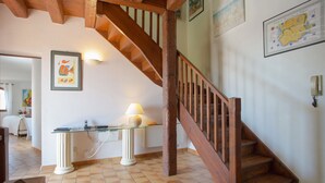 A wooden staircase with a white railing, a glass table with a lamp, and a map on the wall.