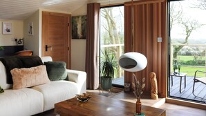 A modern living room with a white sofa, a wooden coffee table, and a large window with a view of the outdoors.