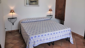 A bedroom with a bed, two wall-mounted lamps, a framed picture, and a wooden door. - Sea View in Positano 1 (Positano)