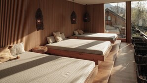 A modern bedroom with three beds aligned along a wooden wall, a large window, and a view of a building outside. - Bergrose Hideaway (Strobl)