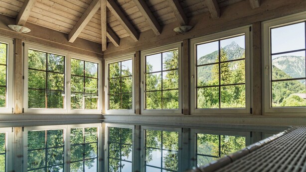 A large room with high ceilings and large windows offering views of a forested mountain area. - Bergrose Hideaway (Strobl)