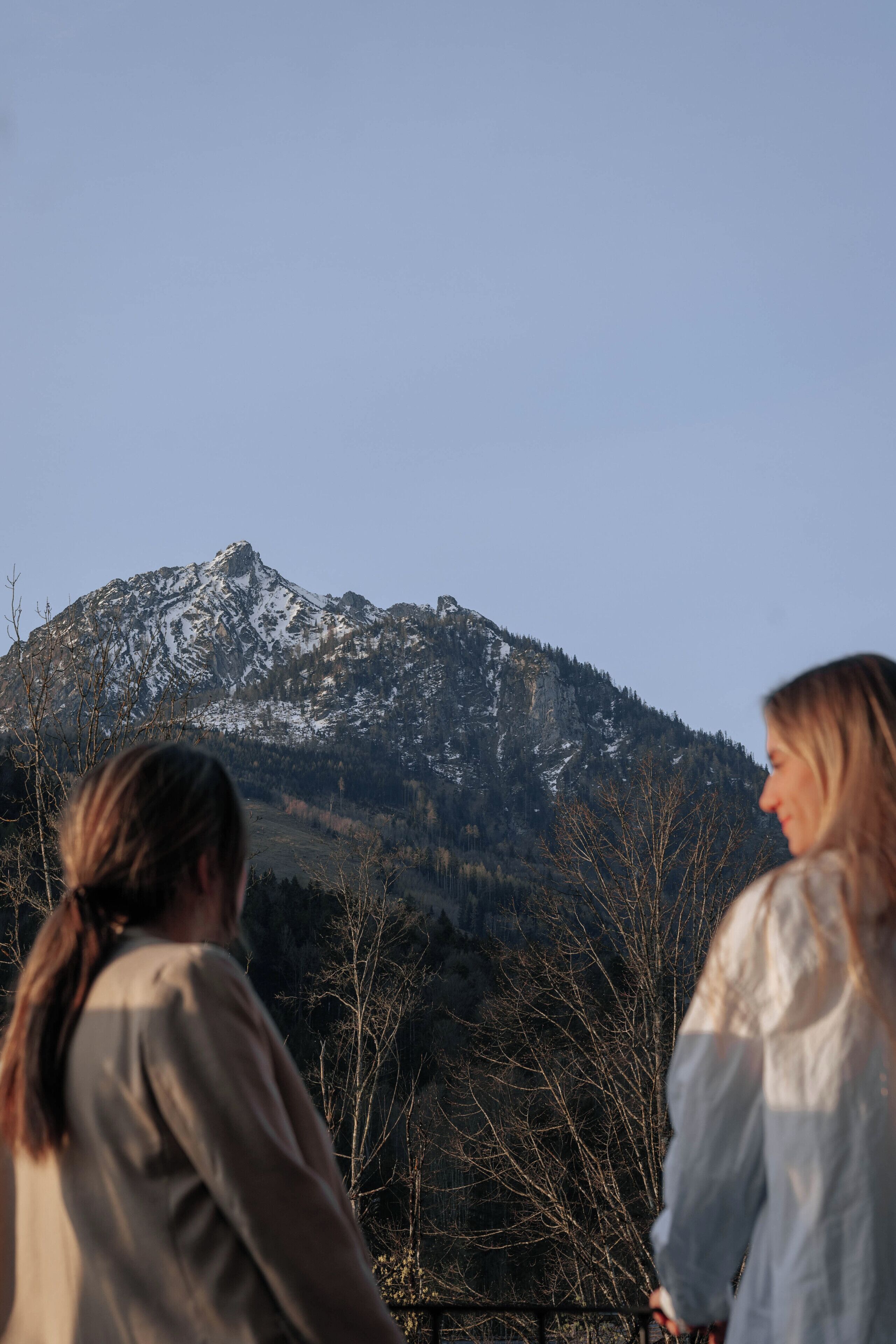 Duas pessoas caminham em direção a uma montanha com picos nevados.