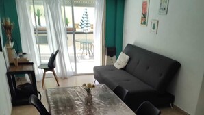 A dining area with a table and chairs, a sofa, and a view through a glass door to an outdoor patio. - Cómodo, Amplio y Seguro Apartamento Familiar a Pasos del Metro en Buenos Aires (Buenos Aires)