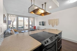 Una cocina moderna con una isla central, horno integrado y zona de comedor con sofá y mesa.