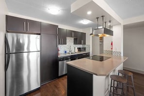 Una cocina moderna con electrodomésticos de acero inoxidable, una isla central y un taburete de bar.