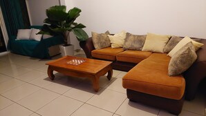 A living room with a brown sofa, a wooden coffee table, and a large potted plant. - Chez Lauret, à la Montagne (LA MONTAGNE)