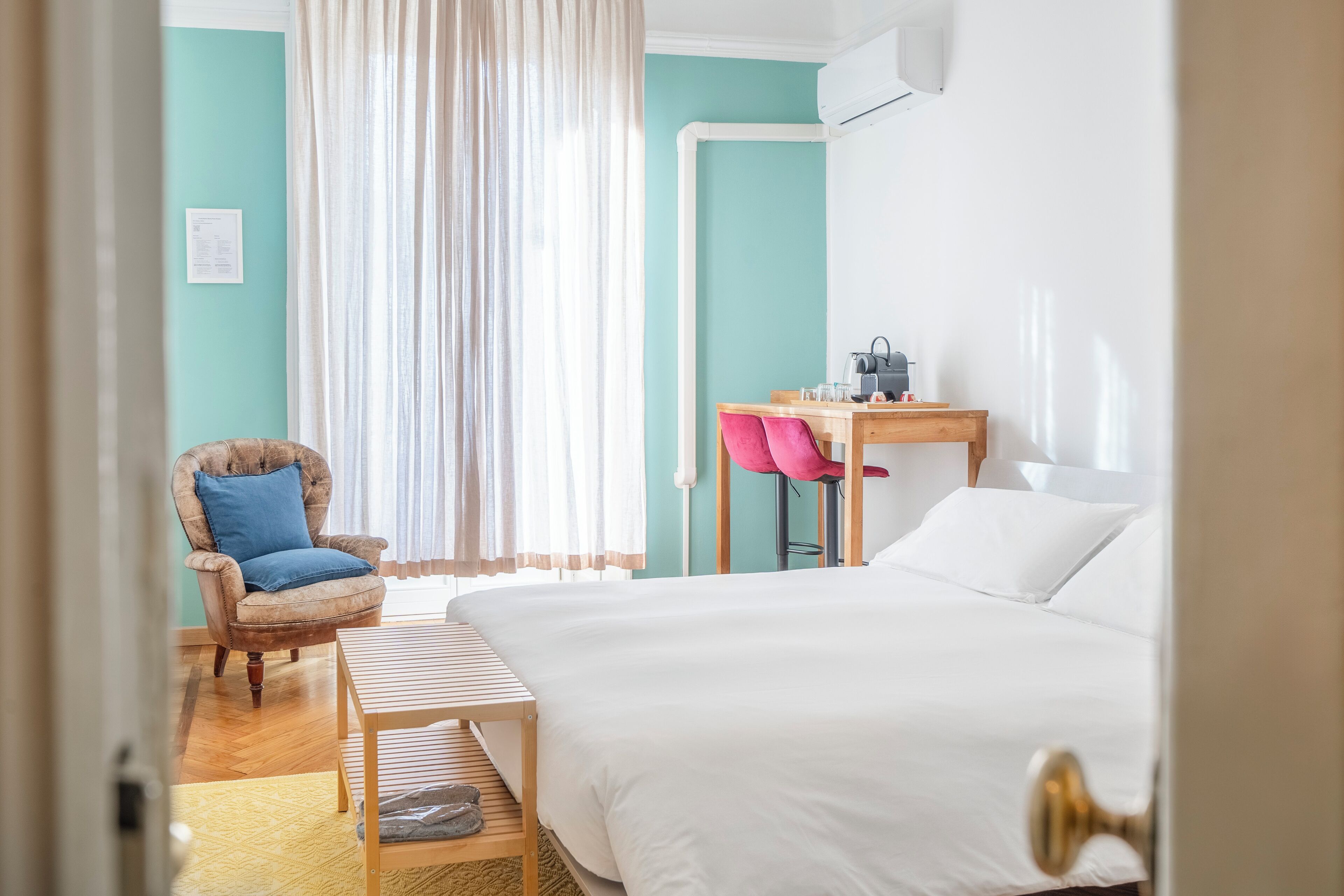Ein Zimmer mit Bett, Schreibtisch, Stuhl und einem Vorhangfenster.