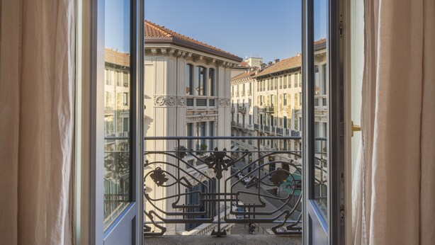 Uitzicht vanaf een balkon met decoratieve metalen hekwerk en een heldere lucht.
