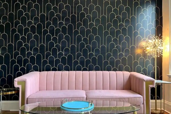 A pink sofa with a glass coffee table in front, against a wall with a geometric pattern. - Mulberry Mansion - OTR - FREE Parking (Cincinnati)