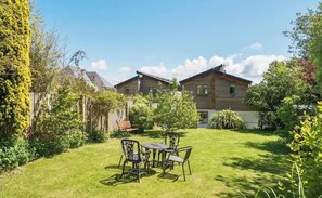 A residential property with a fenced backyard, a patio with chairs and a table, and a wooden house with a sloped roof. - Stylish Estuary View | Sleeps 6 | Parking & Balconies (Saint Ives)