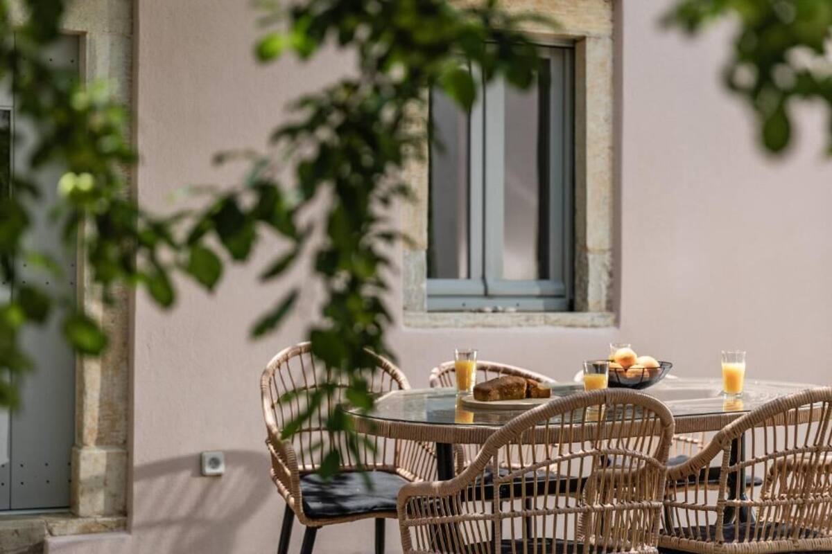 An outdoor dining area with wicker chairs and a table set for breakfast.