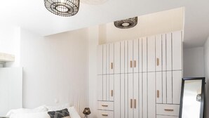 A bedroom with a bed, a wardrobe, and a mirror. - Serenity Village (Naxos)