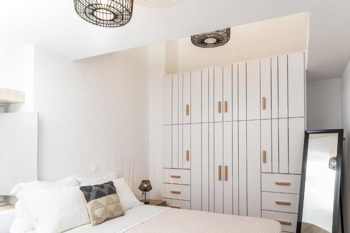A bedroom with a bed, a wardrobe, and a mirror.