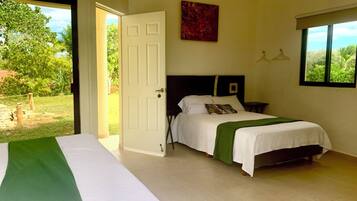 A bedroom with a bed, a window with a view, a door, and a painting on the wall.